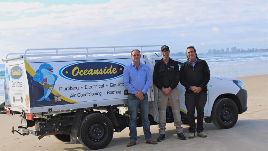 Staff Smiling in front of the Van on the Beach — Reliable Local Plumbers in Gold Coast