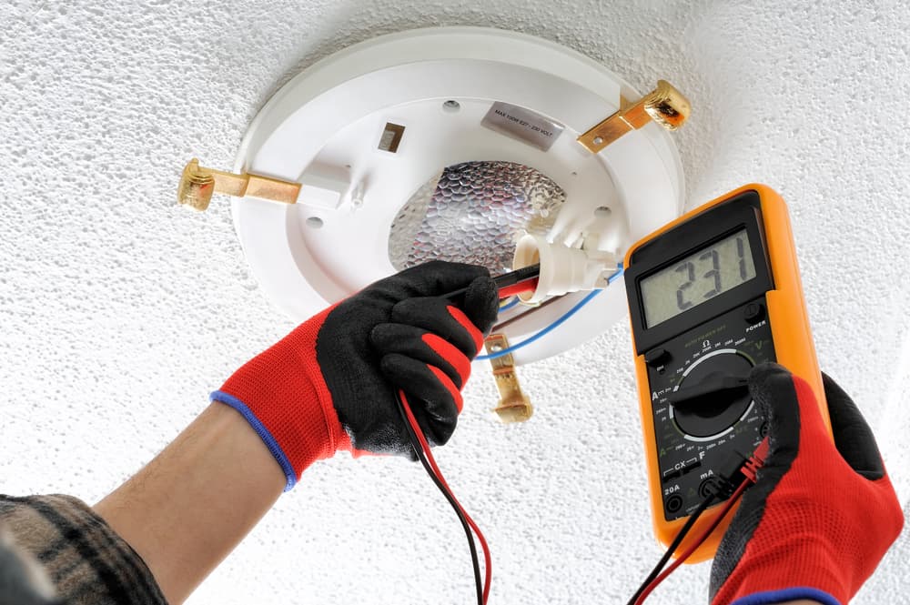 Electrician checking light wattage — Reliable Local Electricians in Helensvale, QLD