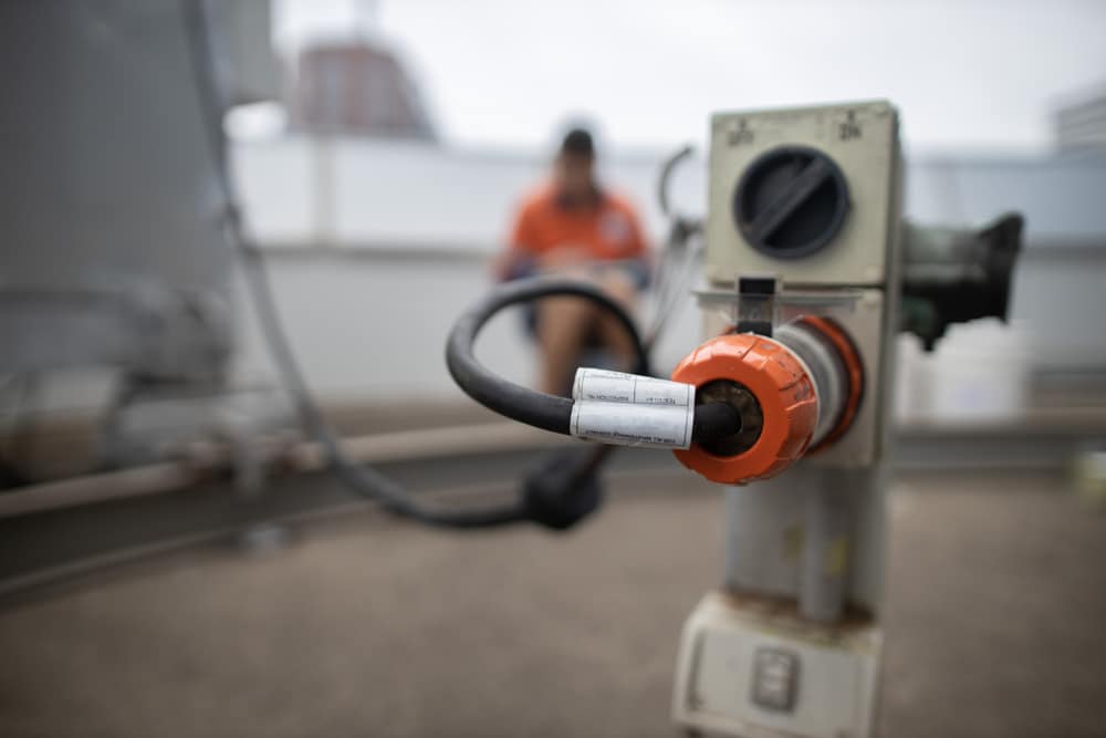 Man Sits On A Gas Pump, Inspecting Paperwork While A Building Maintenance Unit Is Blurred In The Background — Oceanside Services In Burleigh Heads, QLD