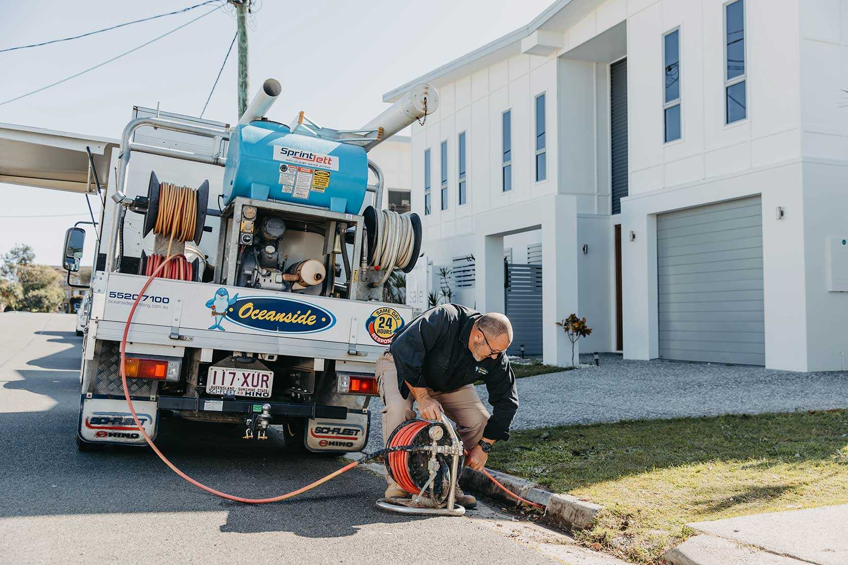 A Man Uses A Hose To Clean The Street, Making It Look Fresh — Oceanside Services In Burleigh Heads, QLD