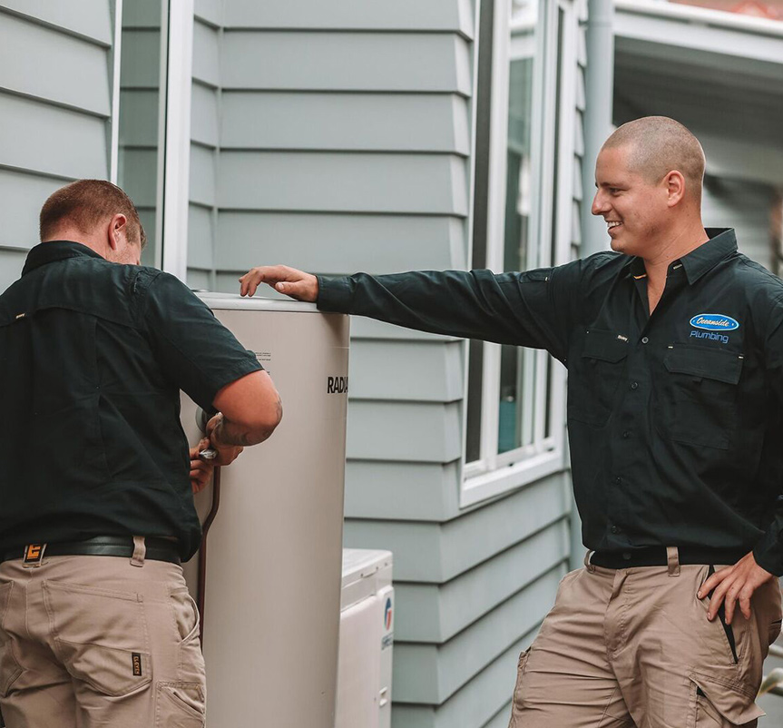 Two Plumbers Standing Next to Hot Water System